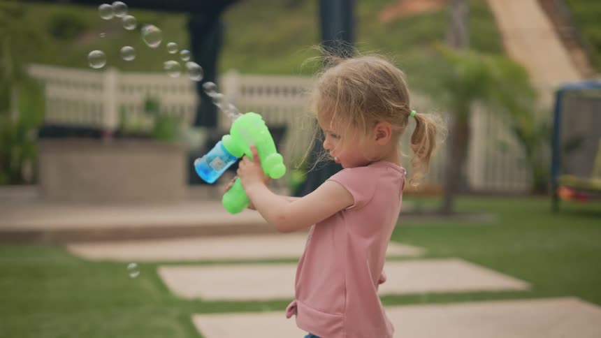 Little girl playing with a bubble gun
