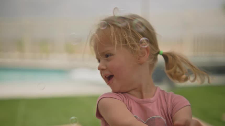 Little blonde girl having fun with soap bubbles