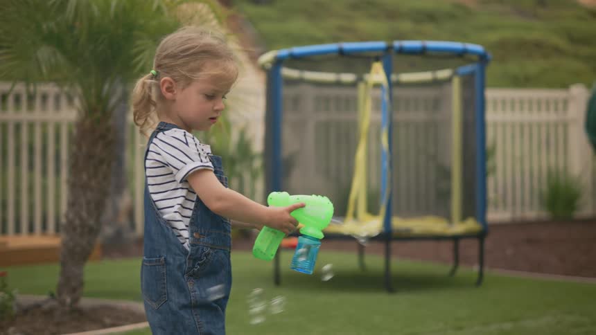 Little girl in a backyard playing with a bubble gun