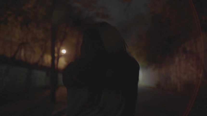 A man stretches his arms while walking down a sidewalk at night