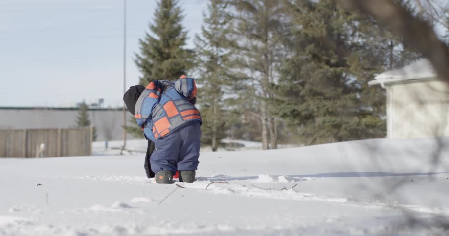A little kid is shoveling the driveway