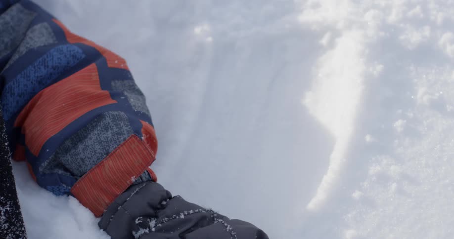 A child laying on the ground in the snow and making snow angels