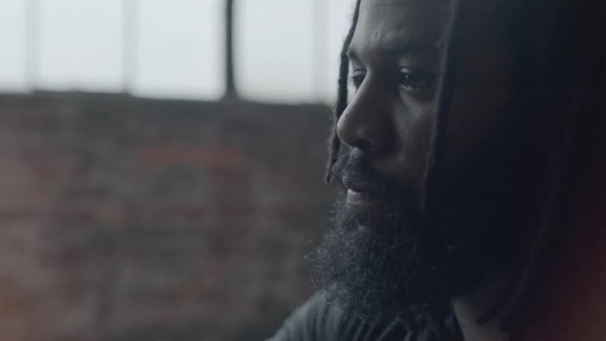 A man wearing dreads is looking at something out of frame