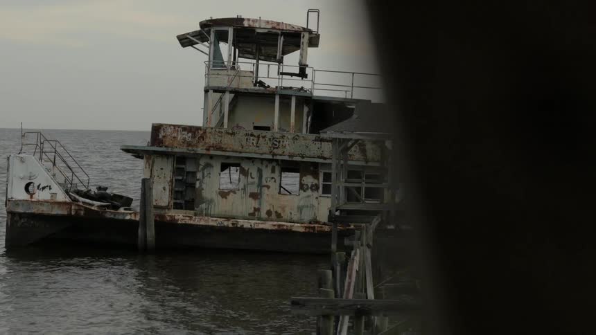 An old, dilapidated structure sits on the ocean