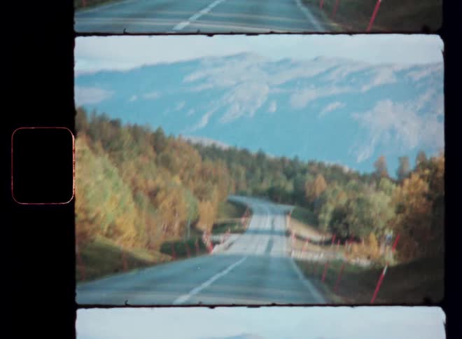 Moving view down a road surrounded by trees and mountains