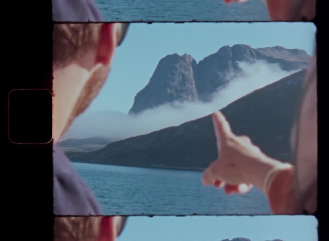 A womans finger pointing to a mountain facing the sea