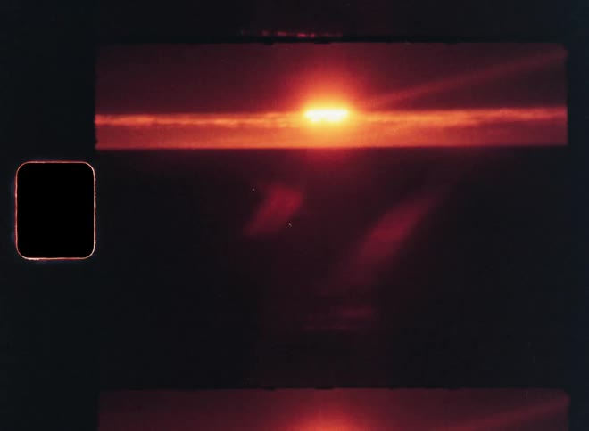 A fiery orange sun sets over a dark seemingly endless expanse