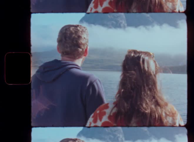 Mans view of a woman from behind and facing a lake with mountains in the background