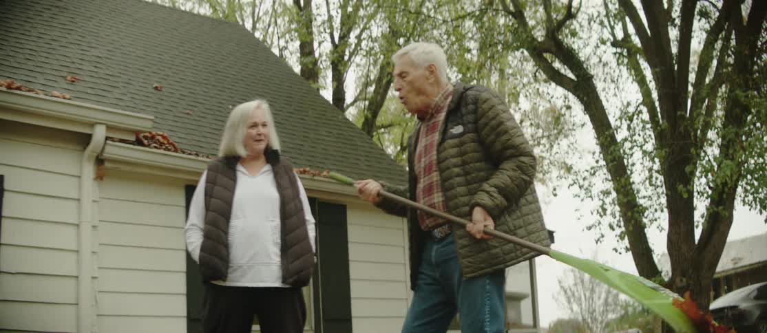 Elderly couple with man holding a rake in backyard