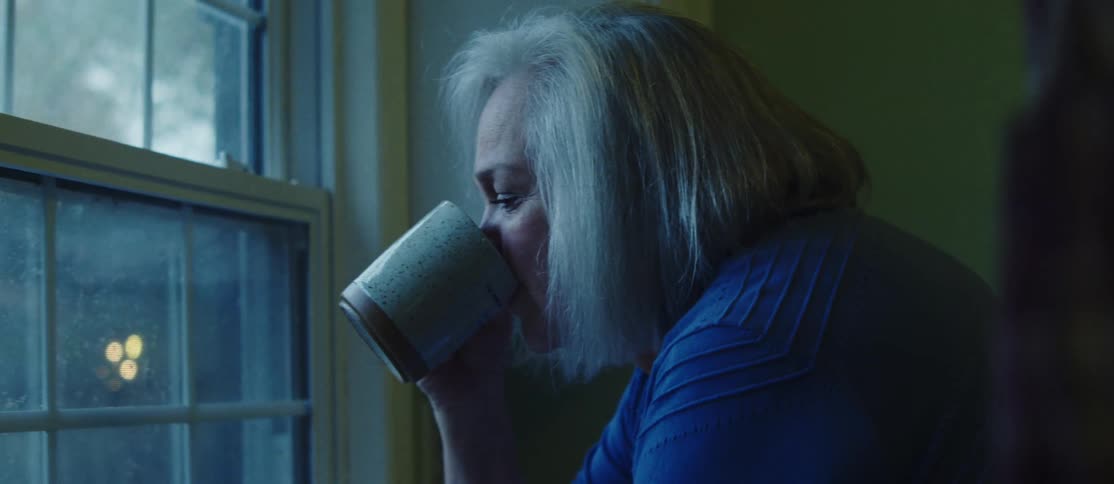 Woman drinking coffee and a man comes to her side