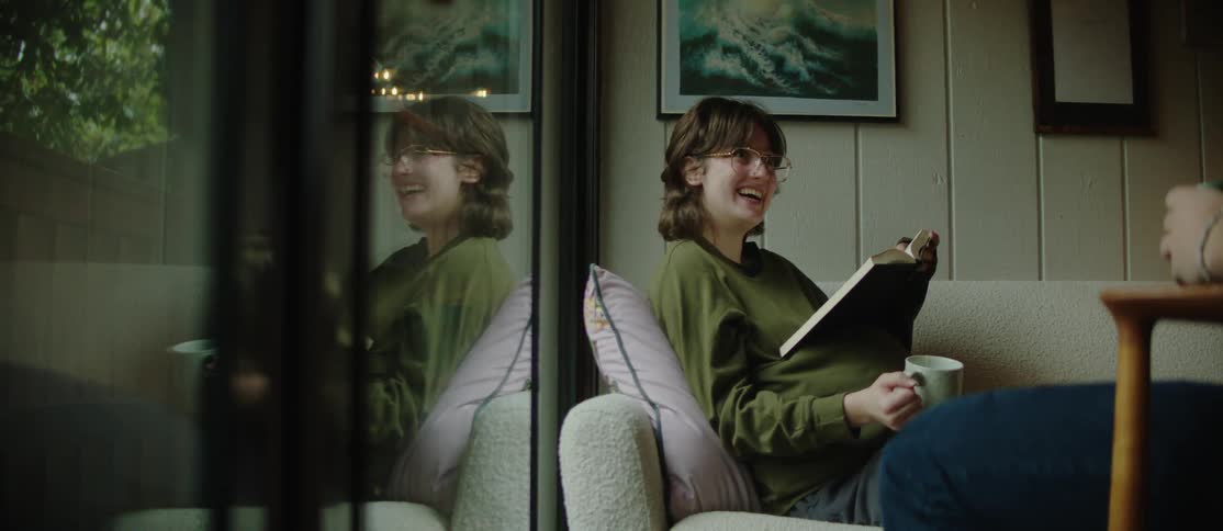 Woman sitting in armchair holding a mug and reading a book