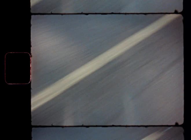 A closeup of road lines seen from a moving vehicle captured on vintage film