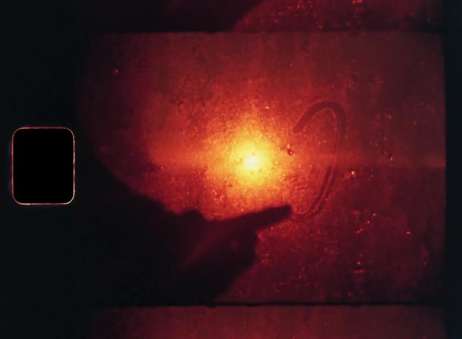 The silhouette of a persons finger drawing a heart on a wall surface