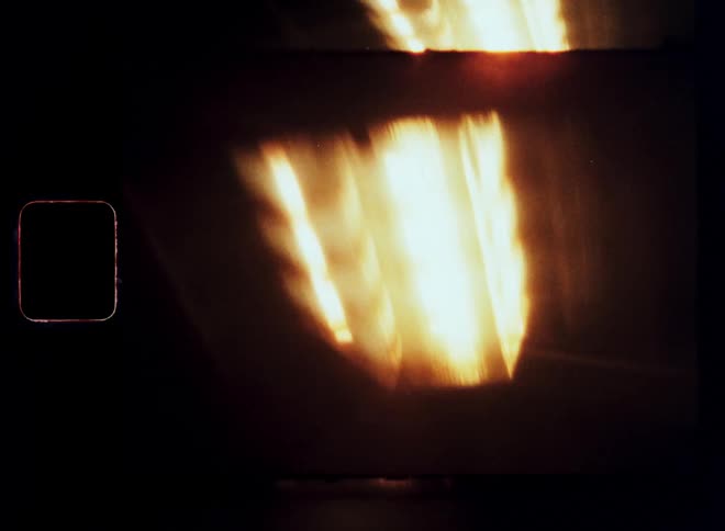 A series of blurry yellow lights streak across a dark grainy background