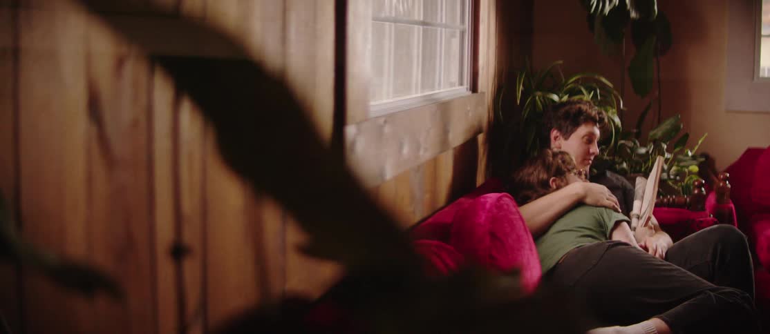 Couple lying together on the couch reading a book