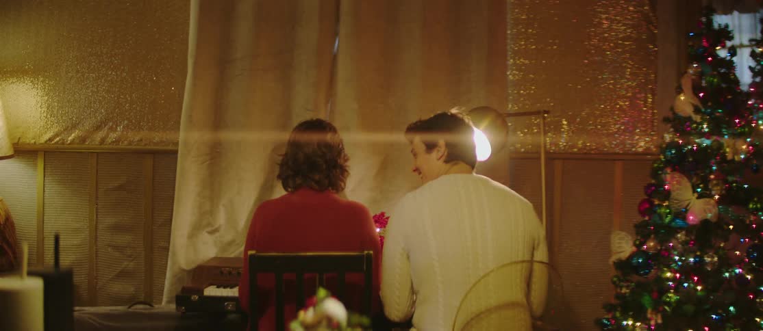 Christmas decorated room with a man and a woman sitting in front of a piano