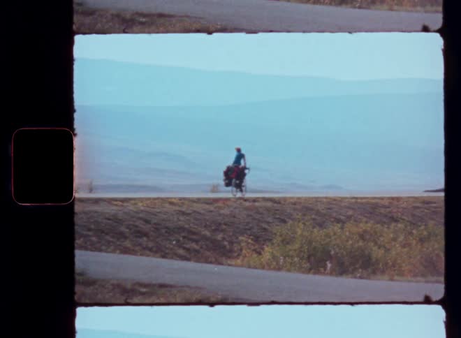 Person riding a bicycle on a paved road in a mountain landscape