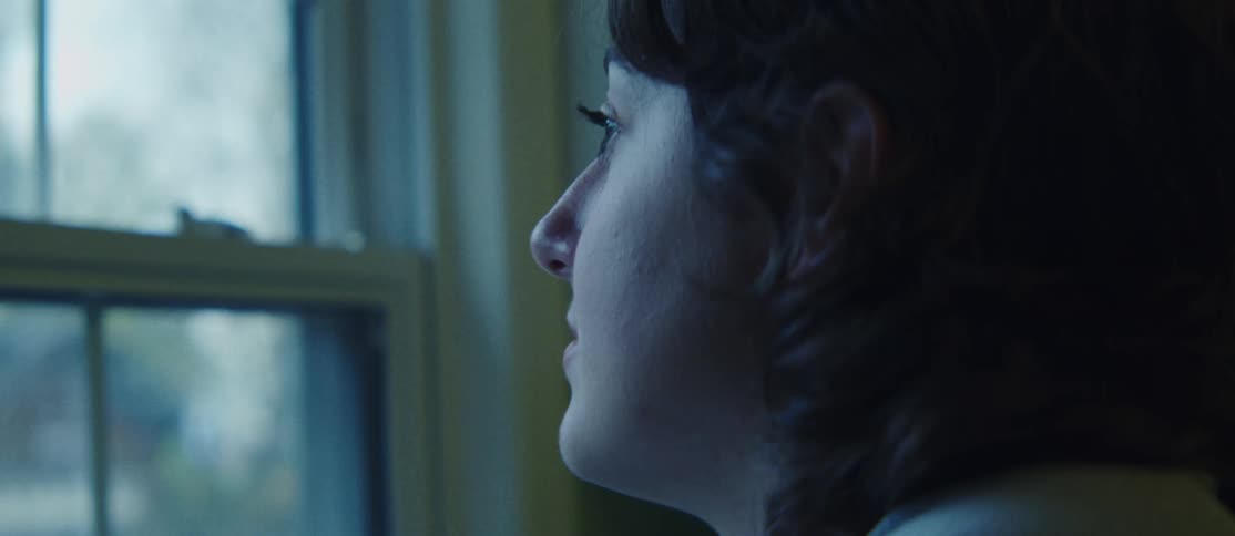 Side portrait of a woman in an indoor space looking out the window