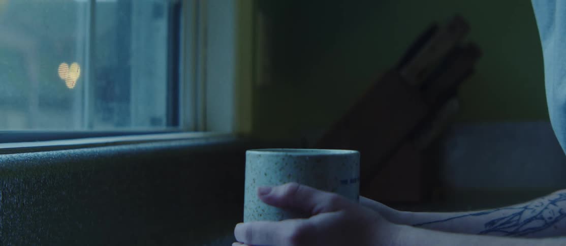 A persons hand is holding a white mug and is running their finger along the outside of the mug