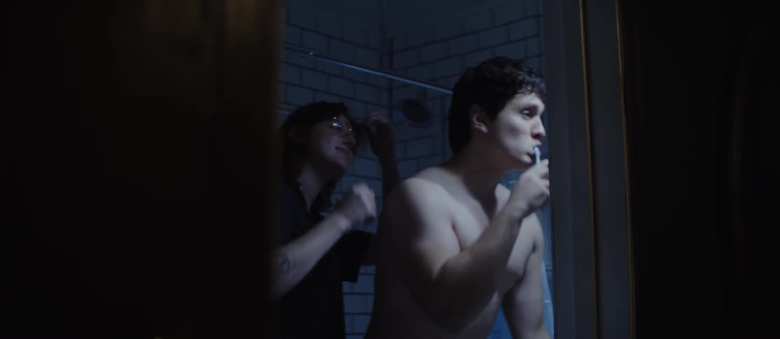 Man in the bathroom brushing his teeth and his girlfriend comes in and gives him a kiss