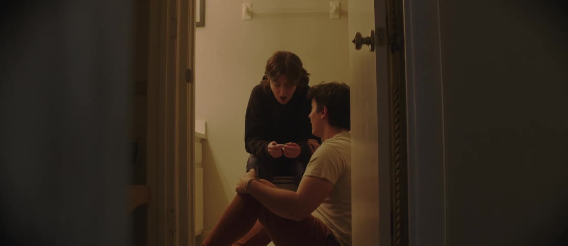 A man and woman are looking at a pregnancy test in the bathroom