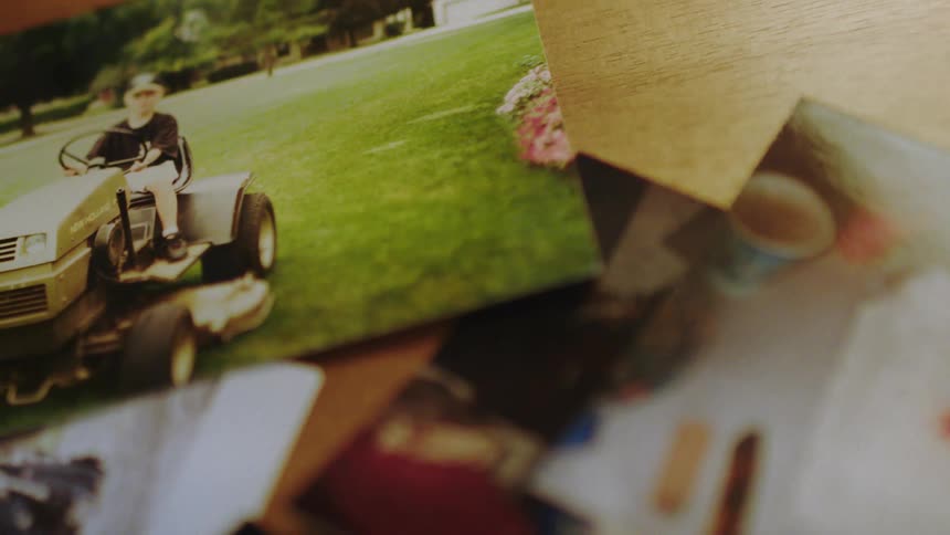 A faded photograph of a man mowing a lush lawn captured among a stack of other forgotten memories