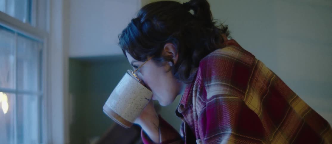 Woman drinking coffee and then her boyfriend comes and gives her a hug and a kiss