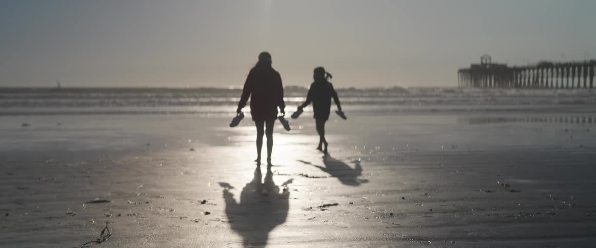 Adult and a child running on the sand at the beach