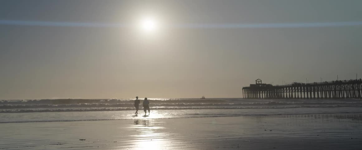 Two people on a beach with the sun in the background