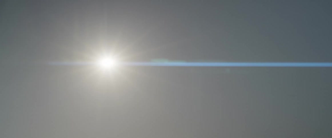The sun is shining brightly in a clear sky and there is a blue flare going to the right