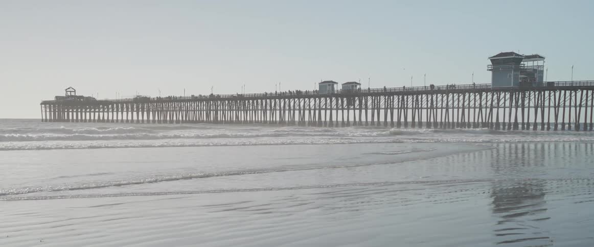 Gentle waves rolling onto the sand near pier