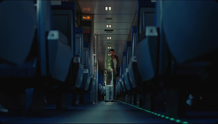Man with a suitcase walking down the aisle of an airplane