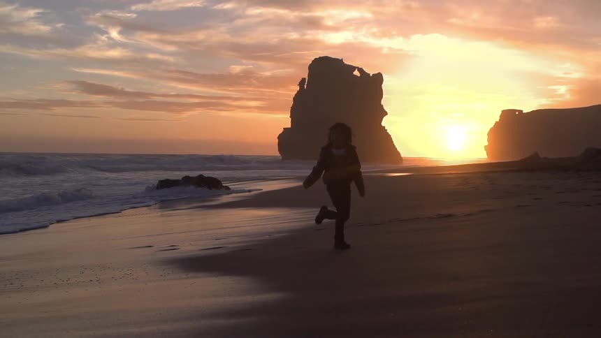 Young person running on a beach at sunset