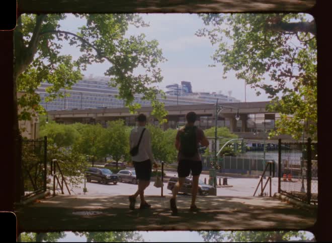 Two men walking down the stairs in a public place facing a highway with vehicle traffic