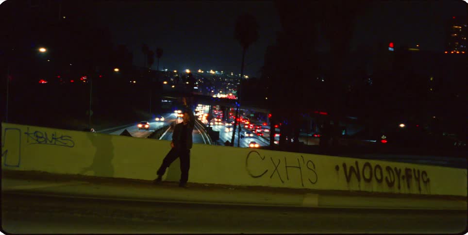 A man is dancing on an overpass at night