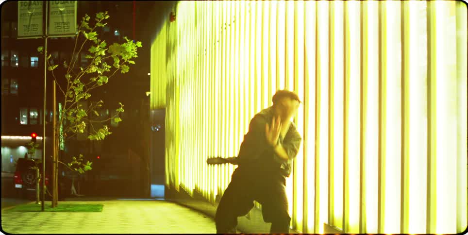 Man dancing on the sidewalk next to a bright building