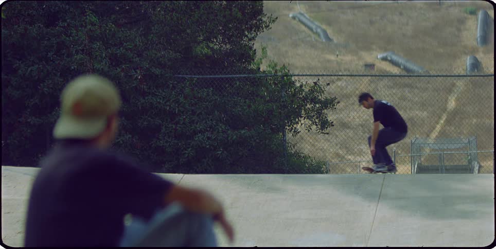 Man clapping for another man doing a trick on a skateboard