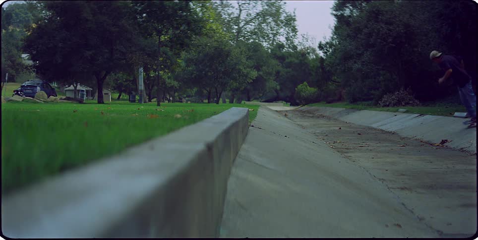 Boy doing skateboarding tricks outdoors with trees in the background