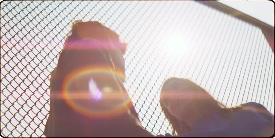 Woman and a man talking next to a fence in broad daylight