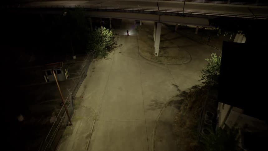 Aerial view at night of a lone person passing below an overpass