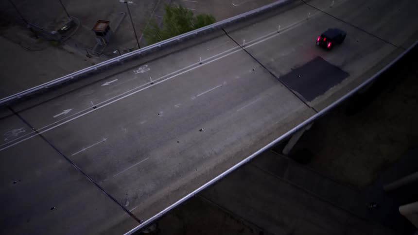 Aerial view of a viaduct and a person on a motorcycle passing below