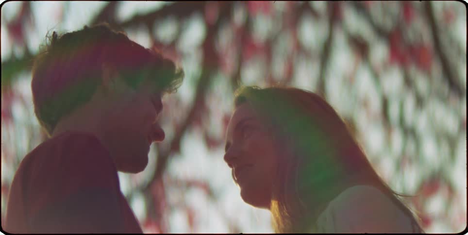 Couple outdoors under a tree looking at each other and talking smiling