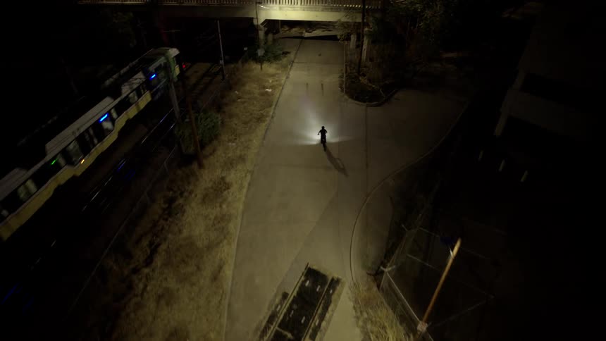 Aerial view of a person on a motorcycle passing under an overpass at night