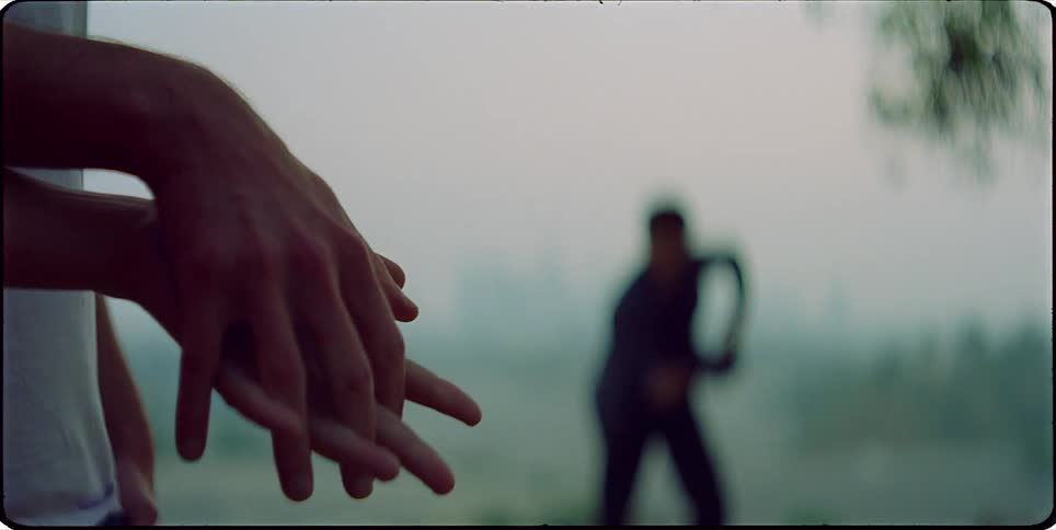 Closeup of hands in the foreground and a person dancing in the background