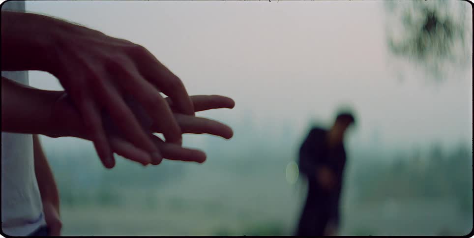 Man dancing in the background and a womans hands in the foreground
