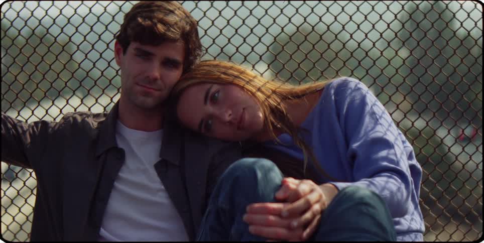 A footage of a man and a woman sitting beside a fence