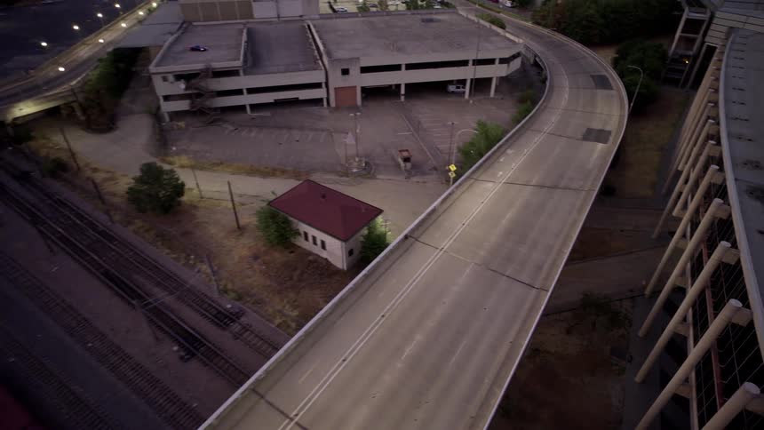 Aerial view of a motorcycle passing under an overpass and next to a train