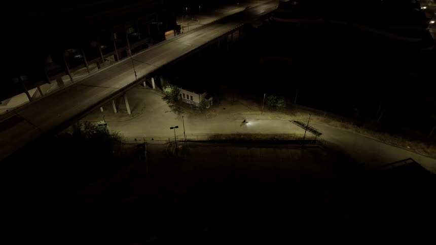 Aerial view of a person on a motorcycle riding along a narrow road at night