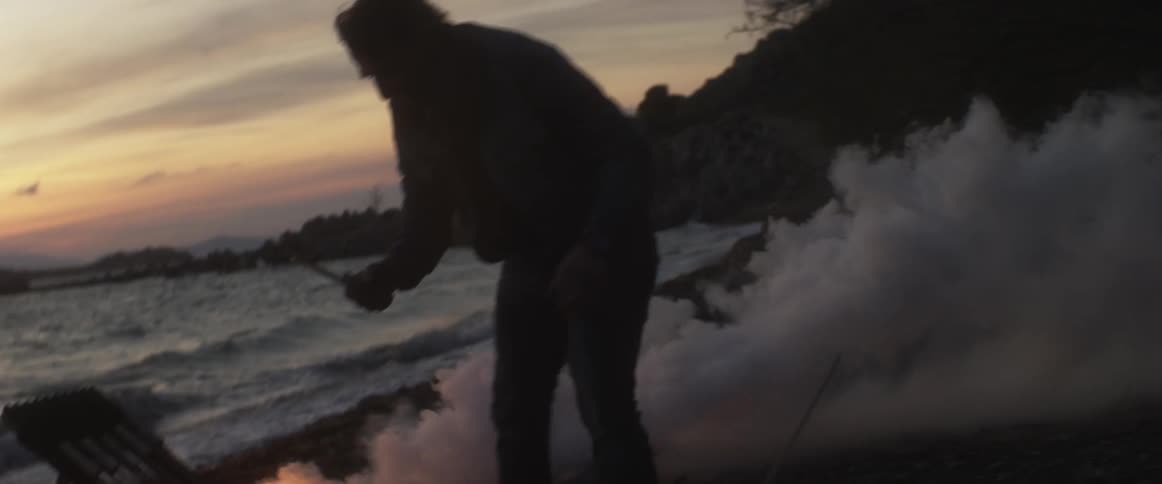 Man breaking a stick over his knee to put in the fire pit