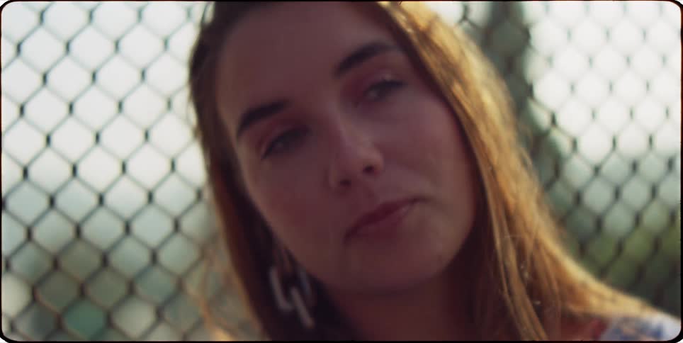A clip of a lady siting beside a wired fence